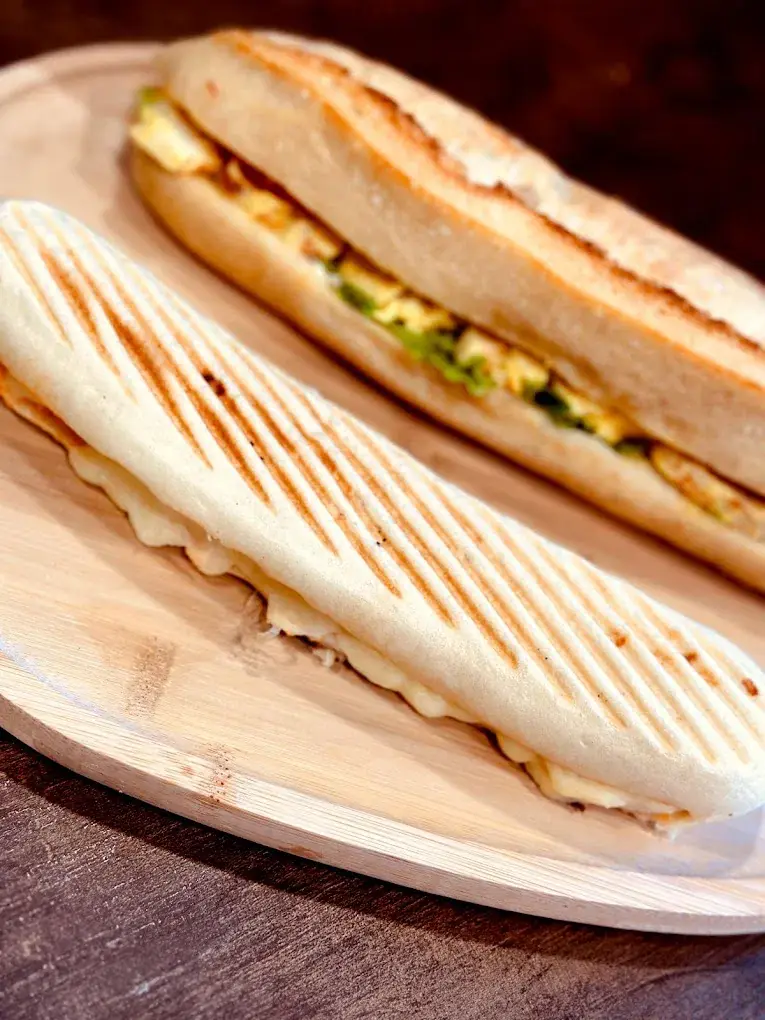 Deux paninis sur une planche en bois, dont un grillé aux traits de gril