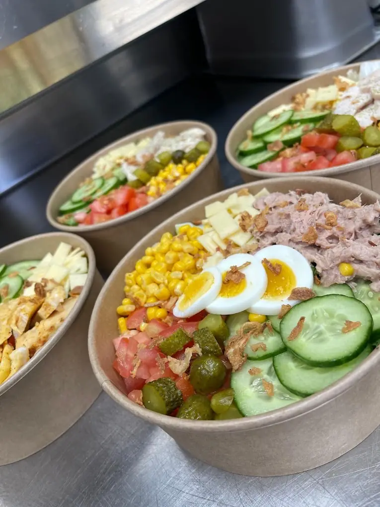 Des salades fraîches en bols : thon, maïs, tomates, concombre, cornichons, œuf dur et fromage
